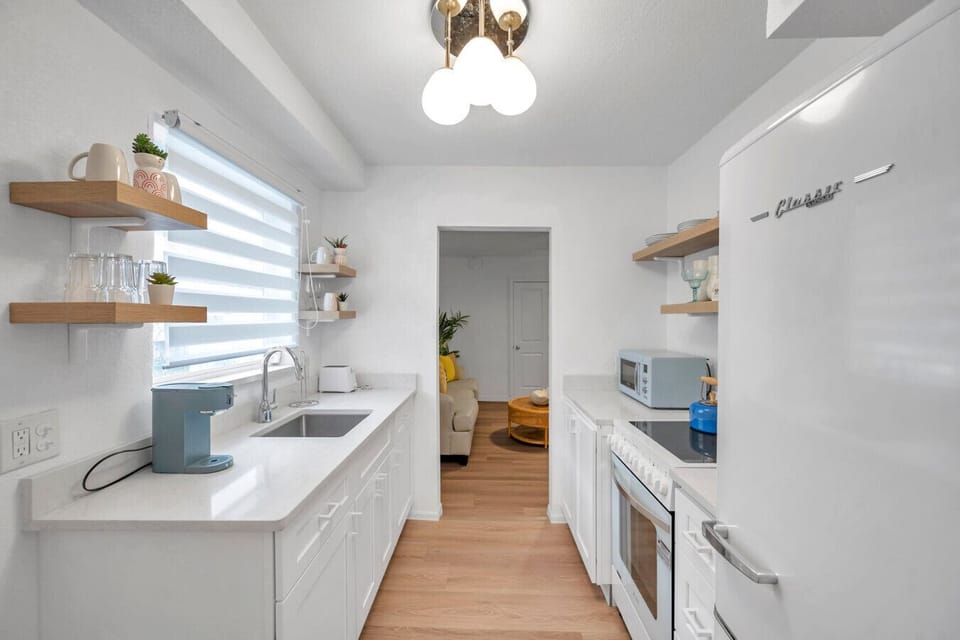 Sleek galley kitchen w/ open shelving, modern finishes, and plenty of space to prep meals.