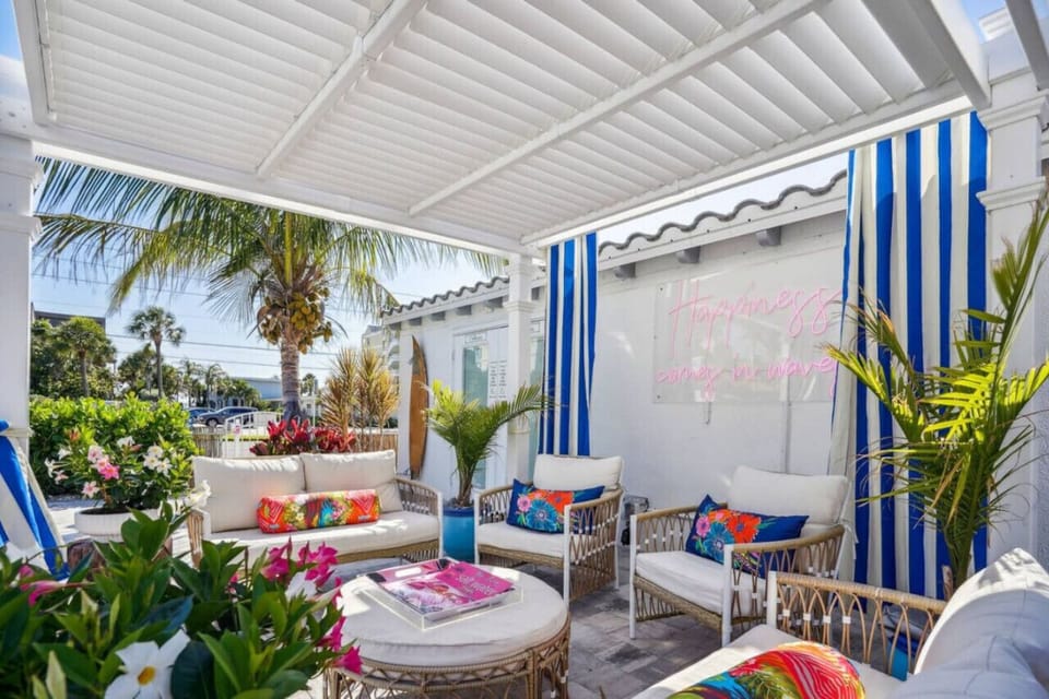 Shaded patio lounge w/ cushioned seating & tropical plants, ideal for morning coffee or evening chats.