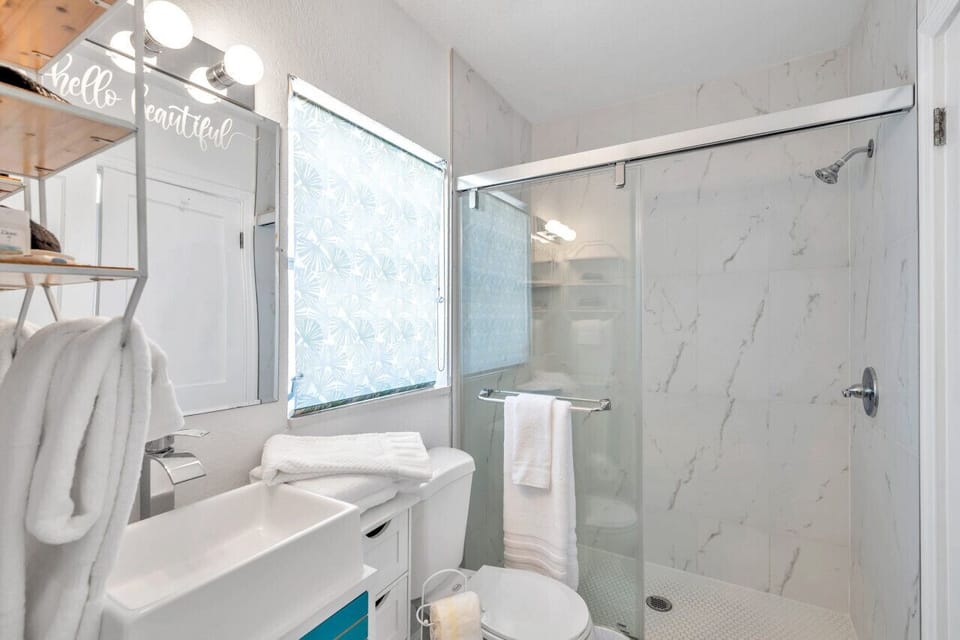 Clean bathroom w/ shower & tub combo, glass doors, and bright white finishes