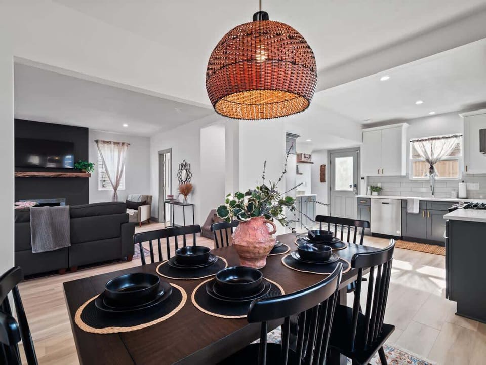 - Open concept kitchen and dining with pendant lighting   - Rustic wooden table set with black dinnerware style   - Seamless flow to living room for easy gatherings  