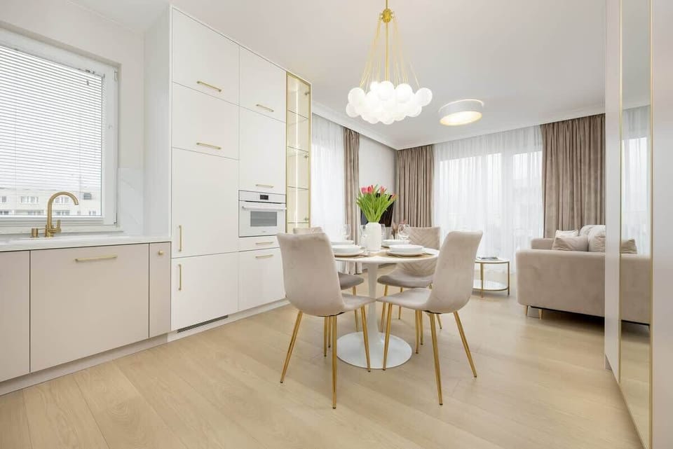 Another perspective of the dining and kitchen area, showcasing the open layout, white cabinetry, and gold-accented decor.

