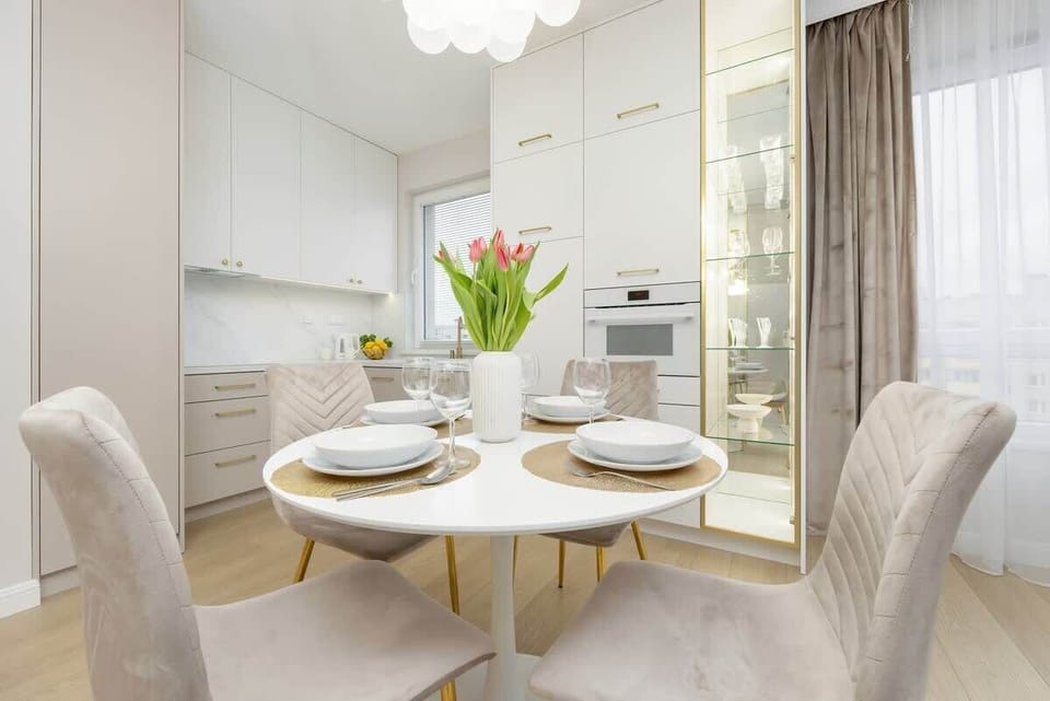 A modern dining area with a round table, elegant chairs, and a fresh bouquet of tulips, creating a stylish and inviting ambiance.

