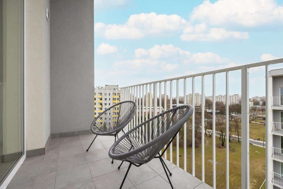A private balcony with black woven chairs, offering a relaxing outdoor space with a view of the surrounding neighborhood.

