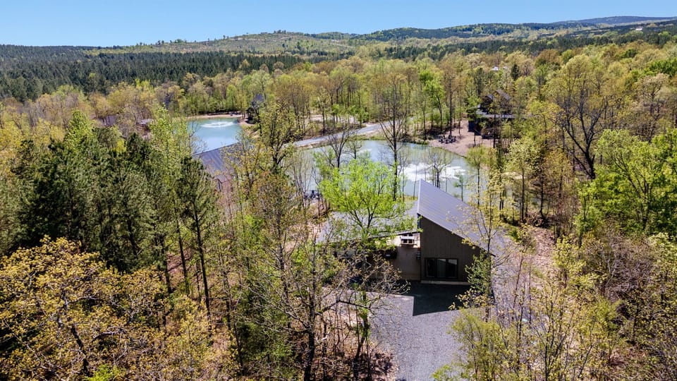 Elevated view of a sleek waterfront abode amidst a sprawling landscape, bridging modern living with nature.