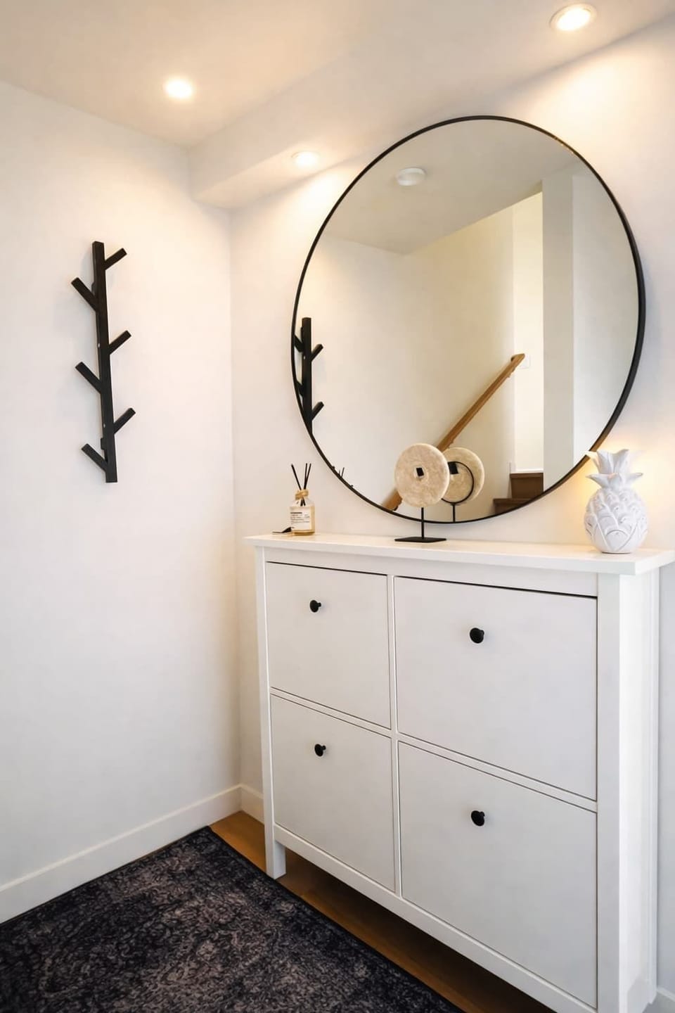 Stylish entryway with a modern console, round mirror, soft lighting, and minimalist decor for a warm first impression.