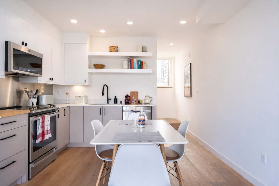 Stylish open kitchen featuring quartz counters, stainless steel appliances, minimalist decor, and a light-filled dining space.