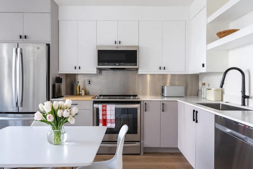 Bright, modern kitchen with sleek white cabinetry, stainless steel appliances, open shelving, and a cozy dining nook.