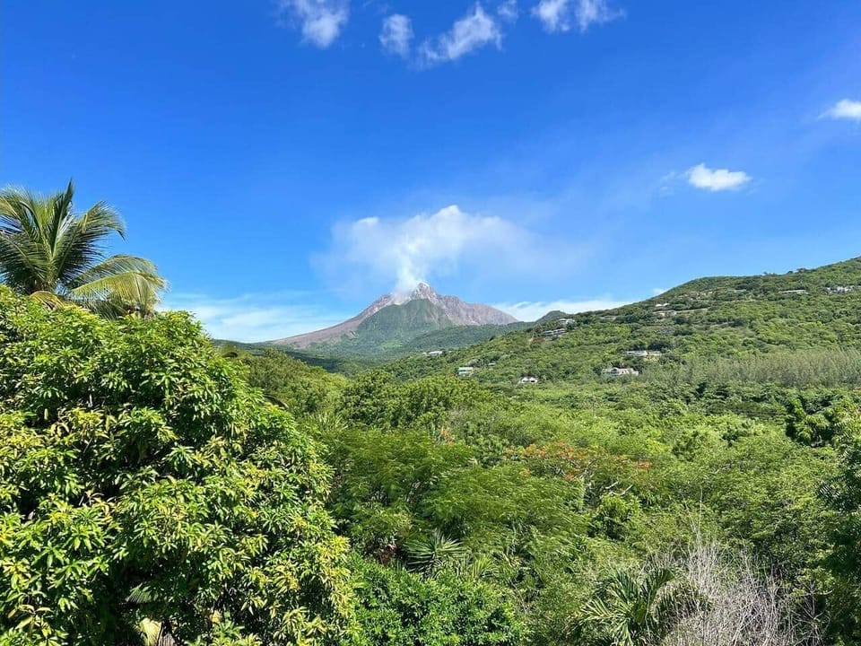 The image presents an immaculate and breathtaking view of the volcano from the yard of the house. The clear, open landscape allows the volcano to stand prominently in the background, enhancing the natural beauty of the property.