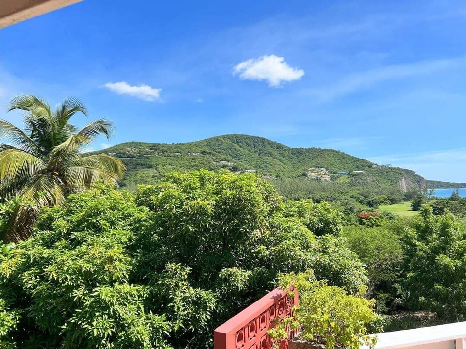 The photograph shows the property set against a mountainous backdrop, with the landscape gradually leading down into the sea.