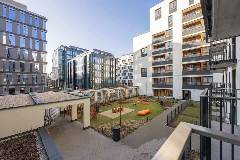 A view of the well-maintained courtyard of the residential complex, featuring green areas, pathways, and contemporary architecture.

