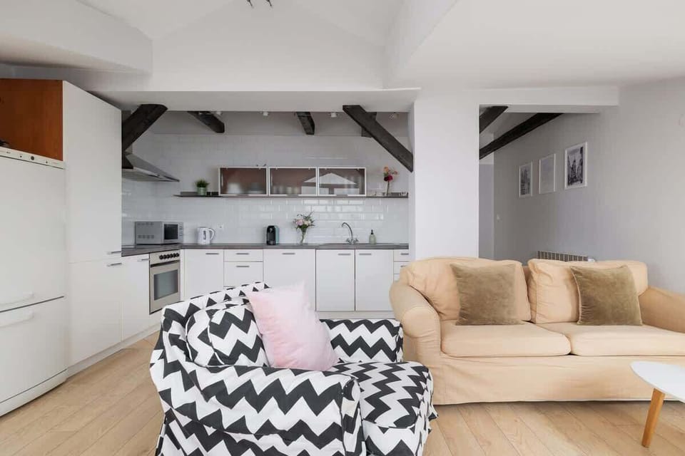 Yet another view of the sloped-ceiling living space, with a cozy arrangement of seating and a floor lamp in the corner.

