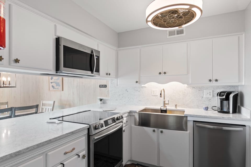 Your pristine white kitchen sparkles with marble countertops and modern appliances, ready for culinary adventures.