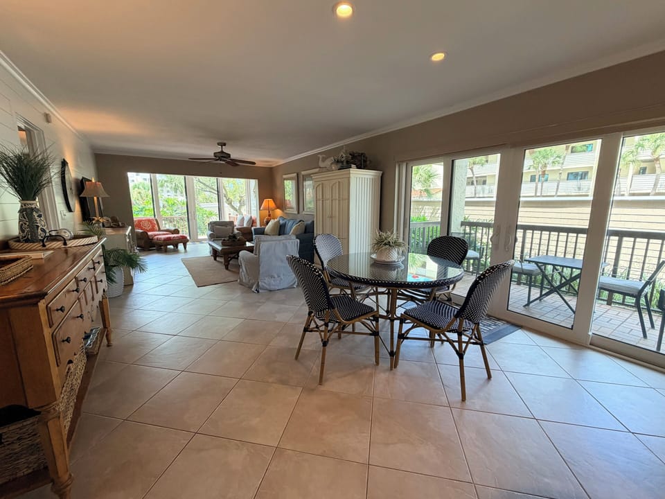 An inviting open-concept living and dining space where you can gather for meals at the elegant round table or unwind on the plush seating, all while enjoying natural light from floor-to-ceiling windows.