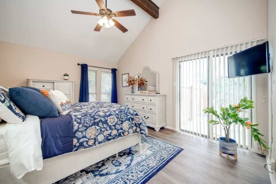 Beautiful primary bedroom with vaulted ceilings, private patio access, cozy bedding, and a flat-screen TV for ultimate comfort and relaxation.