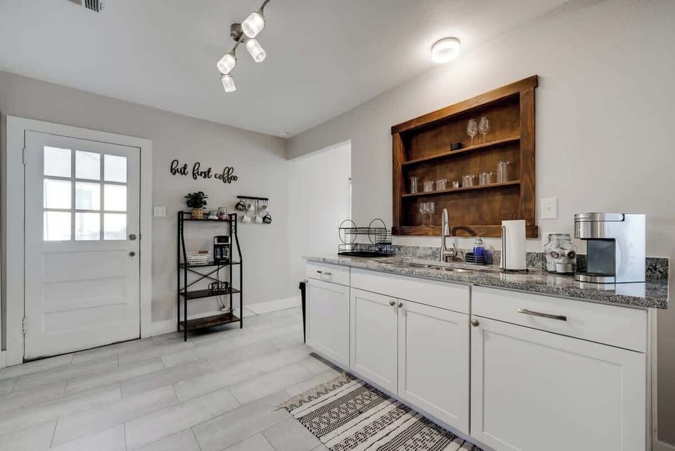 Bright kitchen with granite countertops, open shelving, and all the essentials for your stay.