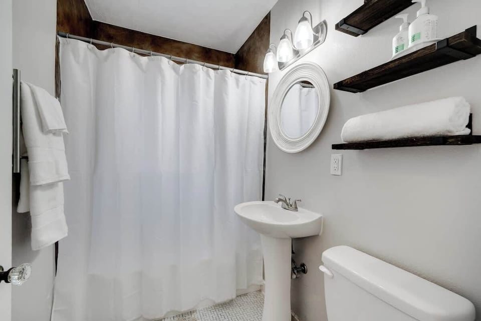 Clean and stylish bathroom with rustic shelving, fresh towels, and all the essentials you’ll need