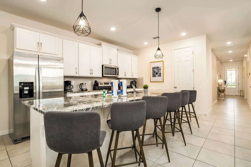 Spacious modern kitchen with sleek marble island and seating for six—perfect for family gatherings.