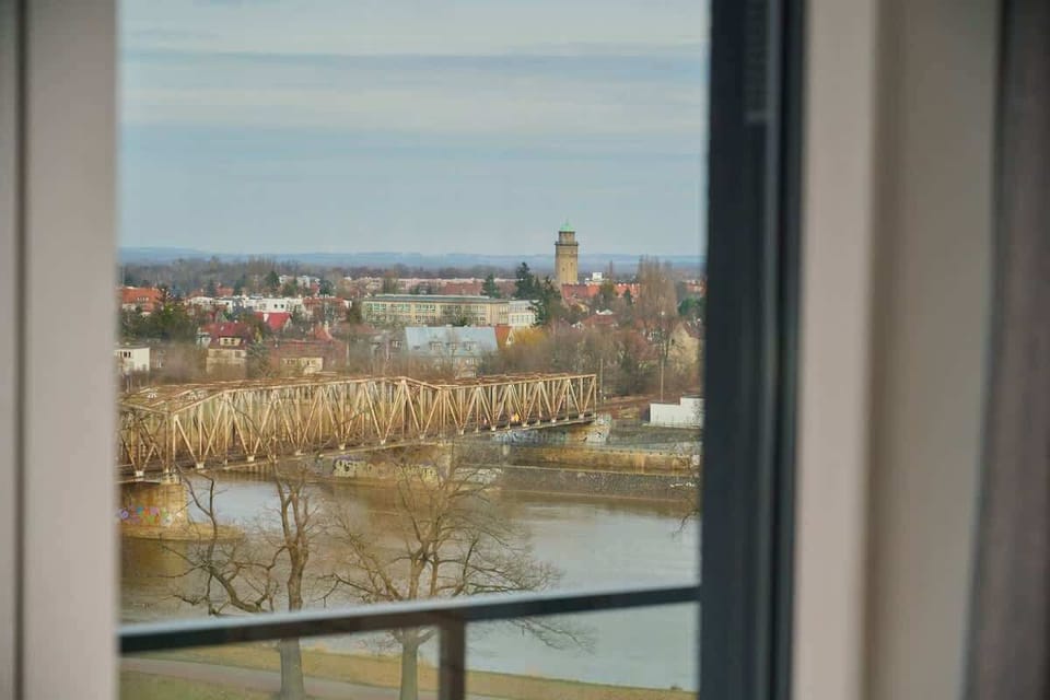 A picturesque cityscape view from the apartment window, overlooking the river and the historic rooftops of the town.

