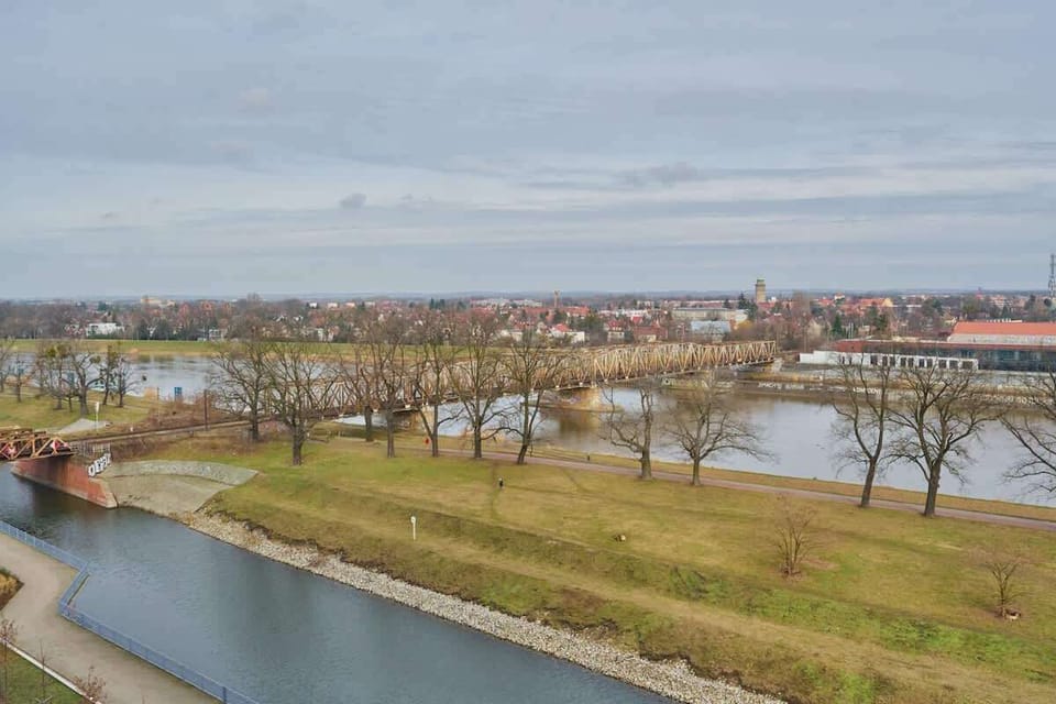 A scenic view of a riverbank with lush greenery and a calm waterway, showcasing the beautiful surroundings near the apartment.

