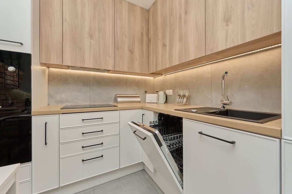 A modern kitchen with sleek white cabinets, wooden countertops, and built-in appliances, offering a clean and practical design.

