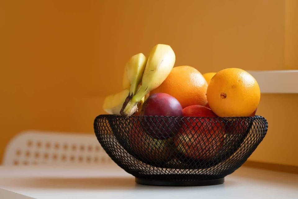 A fresh fruit bowl on a kitchen counter, filled with bananas, apples, and grapes, adding a touch of vibrancy to the space.


