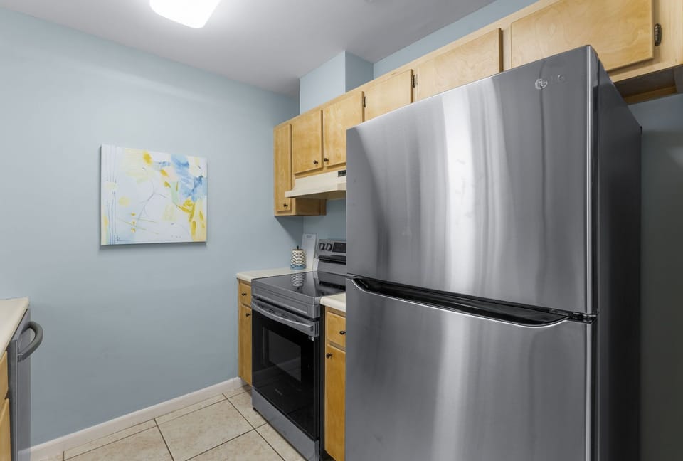 Compact kitchen with stainless steel appliances and light wood cabinets