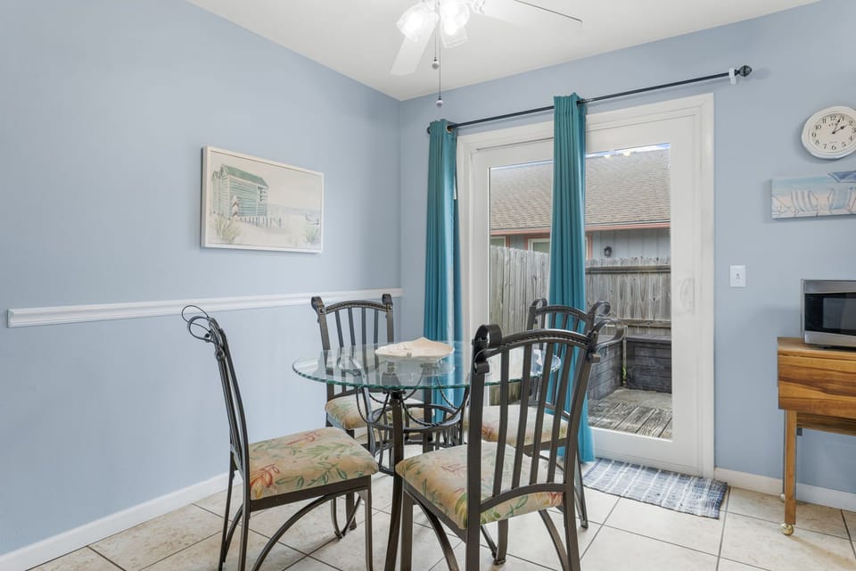 Dining area with glass table and access to a private outdoor space.