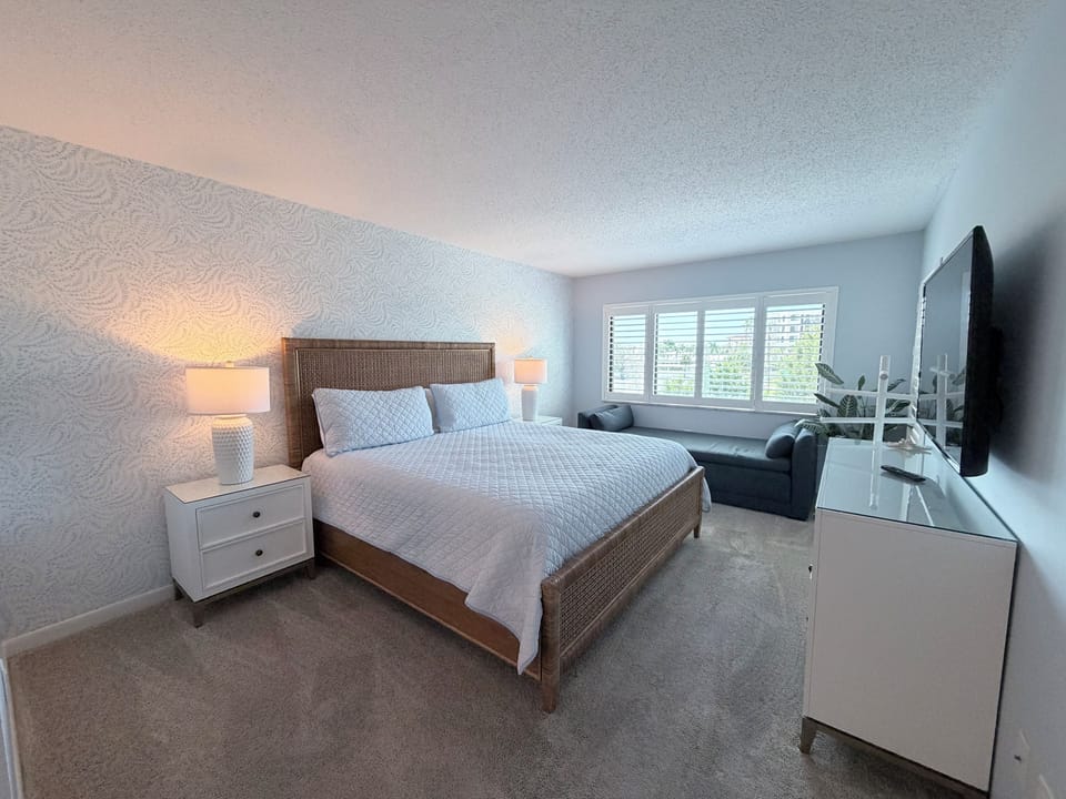 Relax in your peaceful bedroom with soft coastal tones, plush bedding, and gentle natural light from shuttered windows. Unwind on the cozy sectional or catch up on your favorite shows.
