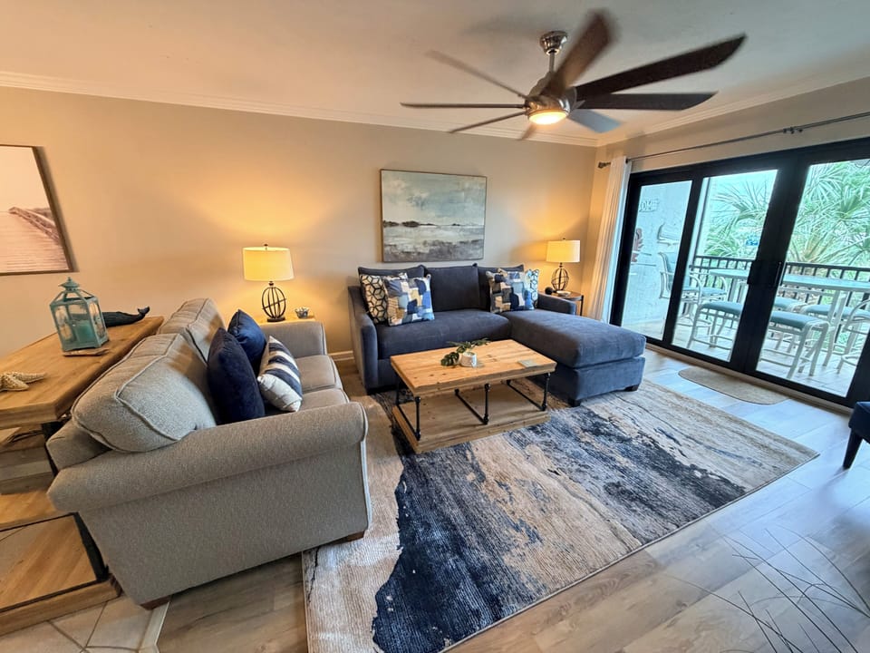 Sink into plush sofas in your beautifully appointed living room, where coastal décor and a soothing ceiling fan create a serene retreat perfect for unwinding after exploring.