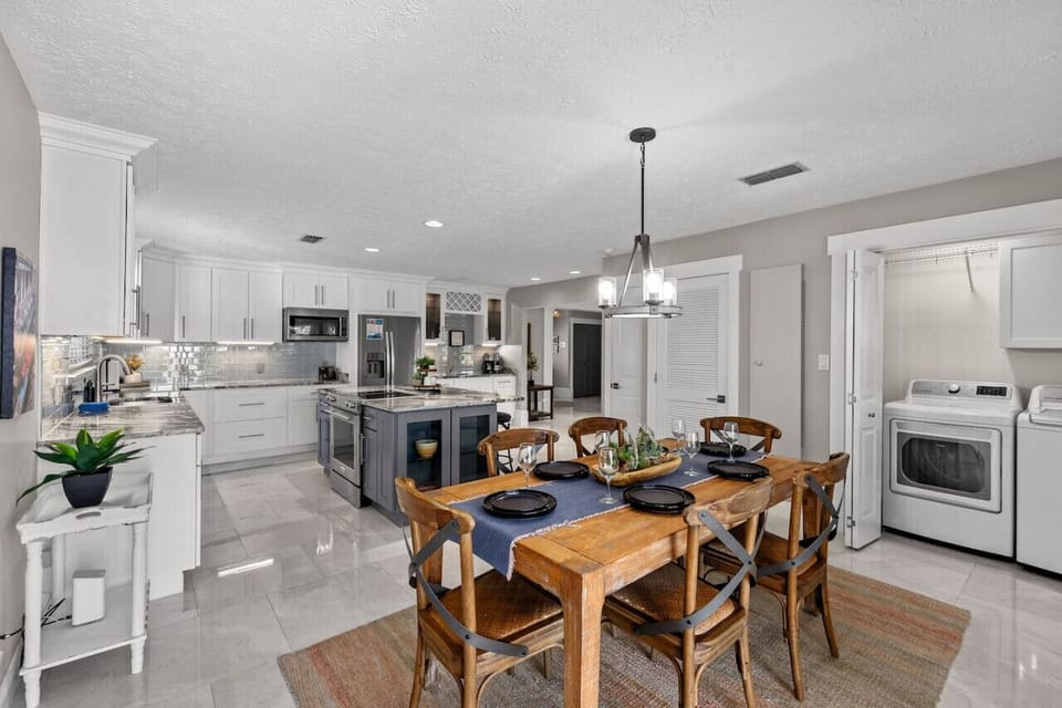 This stylish kitchen and dining space combines modern appliances with a washer and dryer for ultimate convenience, blending functionality and elegance in every corner.