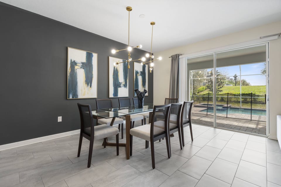 Enjoy our bright dining area featuring a stylish glass table and comfortable seating for eight, perfect for gatherings. The chic dark accent wall and modern lighting create a welcoming atmosphere, enhanced by sliding doors.