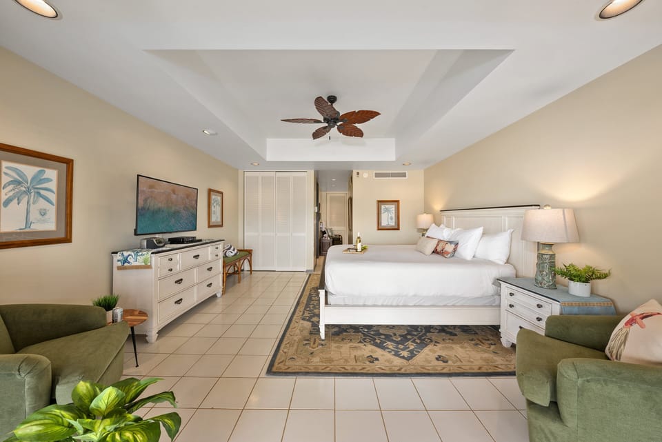 Spacious bedroom featuring a plush king-size bed, flat screen TV and two couch