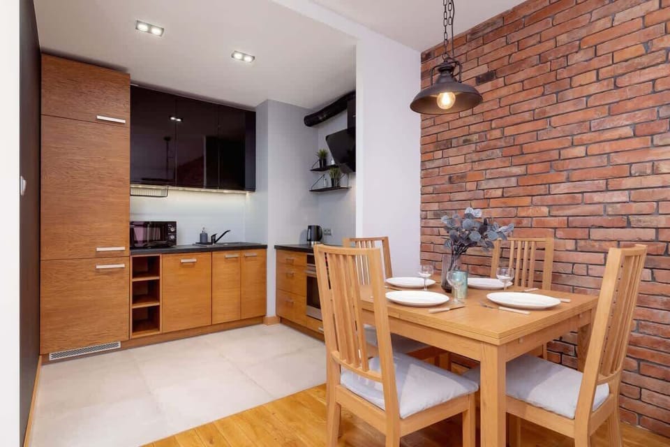 Another perspective of the open kitchen and dining area, emphasizing the combination of wood, brick, and industrial lighting.

