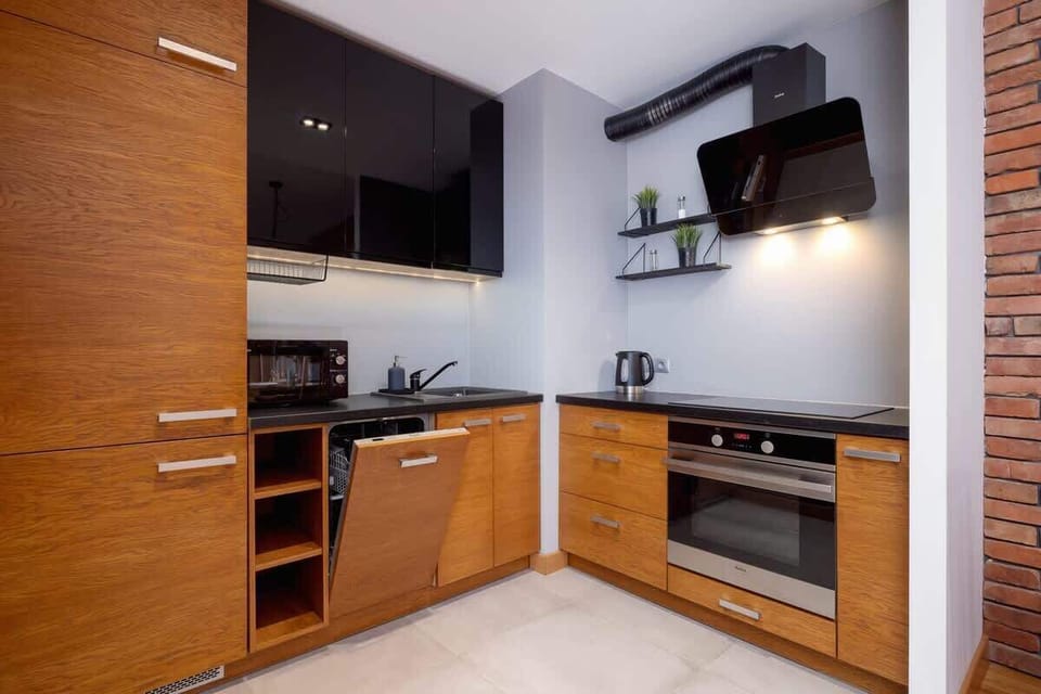 A modern kitchen with wooden cabinets, black countertops, and built-in appliances, blending functionality with an industrial aesthetic.

