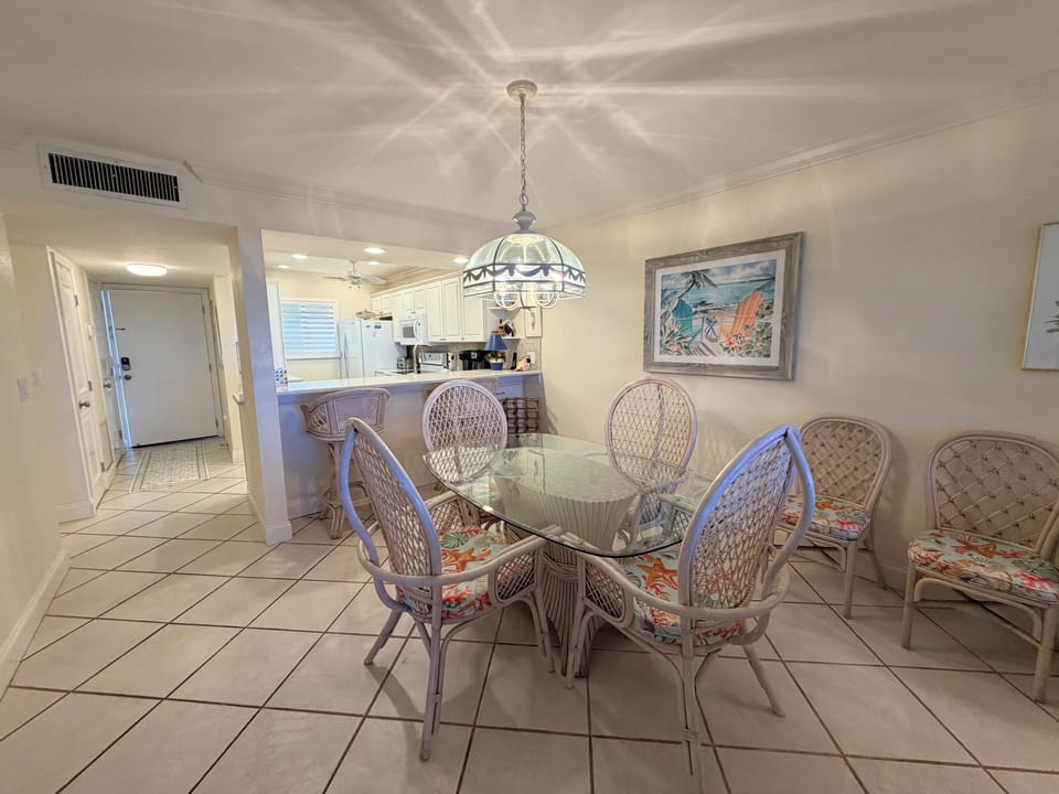 Gather your group around the glass-top dining table, where coastal charm meets comfort beneath a glowing chandelier. You'll share meals and memories in this bright space with the kitchen just steps away.