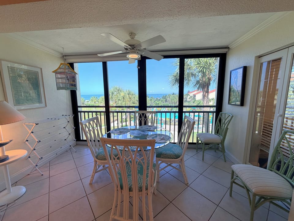 This sun-filled balcony offers your perfect spot to savor morning coffee or sunset views. A dining table invites leisurely meals, while tropical palms and ocean vistas create your serene escape.