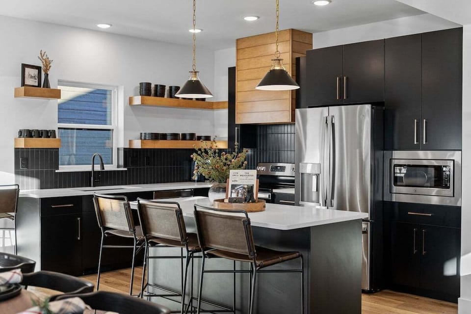 - Whip up snacks, meals, or cocktails in this modern and social kitchen
- Pull up a barstool and enjoy a chat while someone preps your favorite dish
- Bold black cabinetry pairs perfectly with wood accents and pendant lights