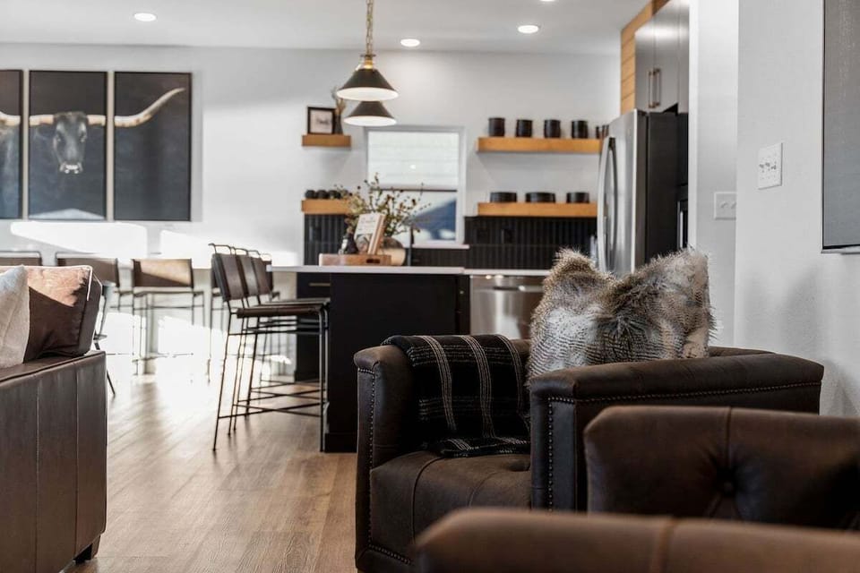 - Sink into the leather armchairs, wrapped in cozy pillows and throws
- The open-concept design keeps the vibe flowing from kitchen to couch
- Bold artwork and rich tones make this the heart of the home for relaxing