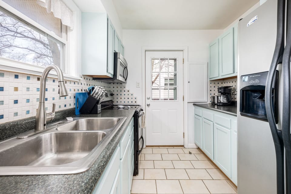 Light-filled kitchen w/ double sink, tiled floors, & ample counter space for easy meal prep