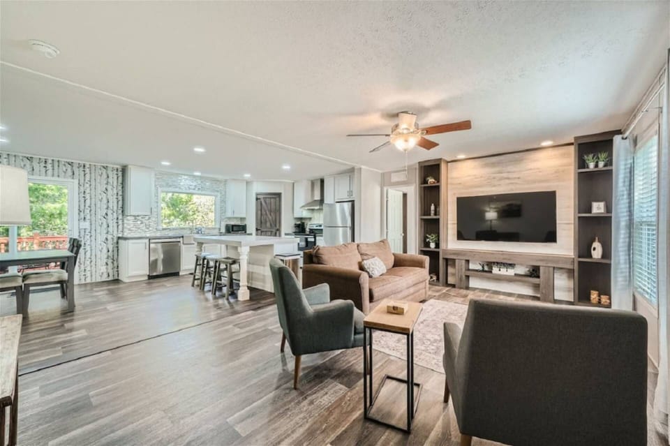 Open floor plan with dining room, bar seating, living room with large TV, couches and chairs