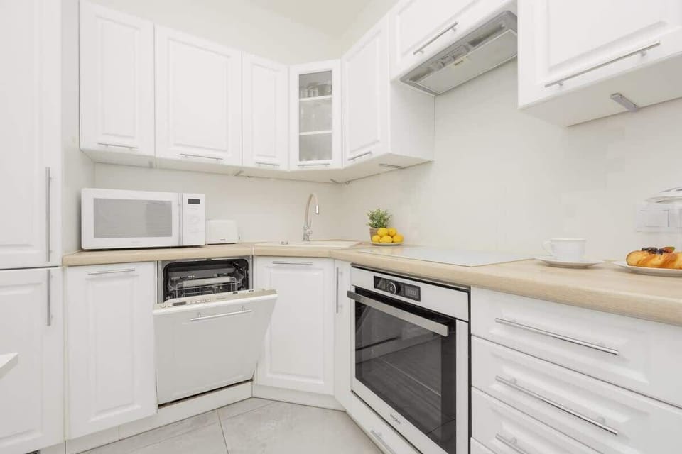 A modern kitchen with white cabinets, beige countertops, and built-in appliances, offering a sleek and functional design.

