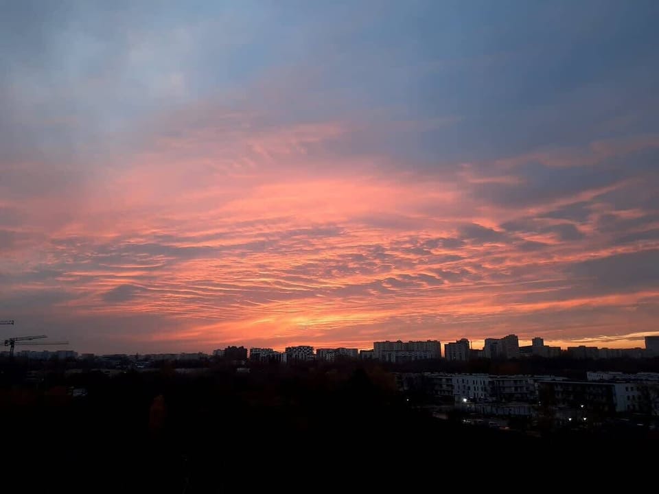 A breathtaking sunset view over the city skyline, with warm orange and pink hues illuminating the sky.

