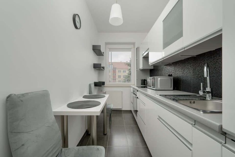 A different angle of the kitchen, showing a large window above the sink, a silver kettle, and a practical workspace.

