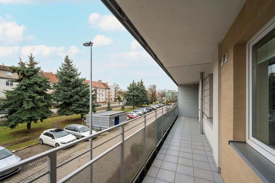 Another perspective of the balcony, highlighting the spacious outdoor walkway with a railing and a suburban view.


