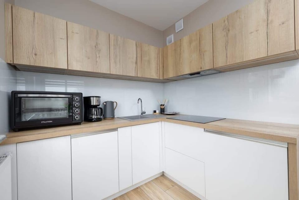 A contemporary kitchen with wooden upper cabinets, white lower cabinets, a built-in microwave, and a clean, minimalist look.


