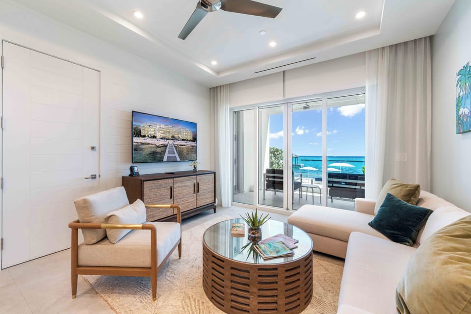Living area with comfy sectional sofa, HD television, and walkout access to the beach. 
