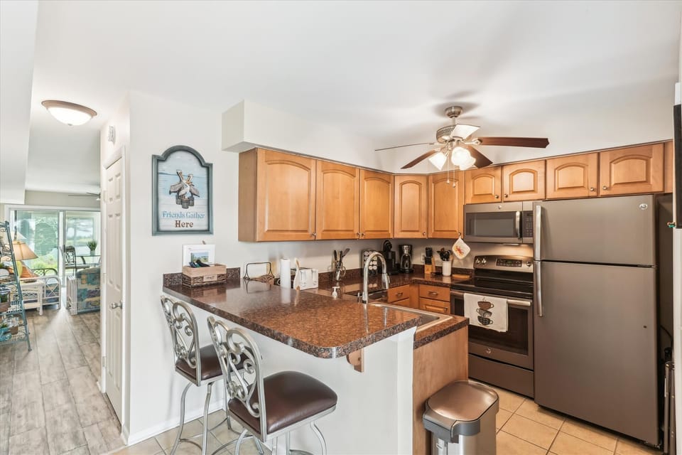 Your fully-equipped kitchen features warm wood cabinetry, granite countertops, and stainless steel appliances, all centered around a breakfast bar where you can enjoy morning coffee.