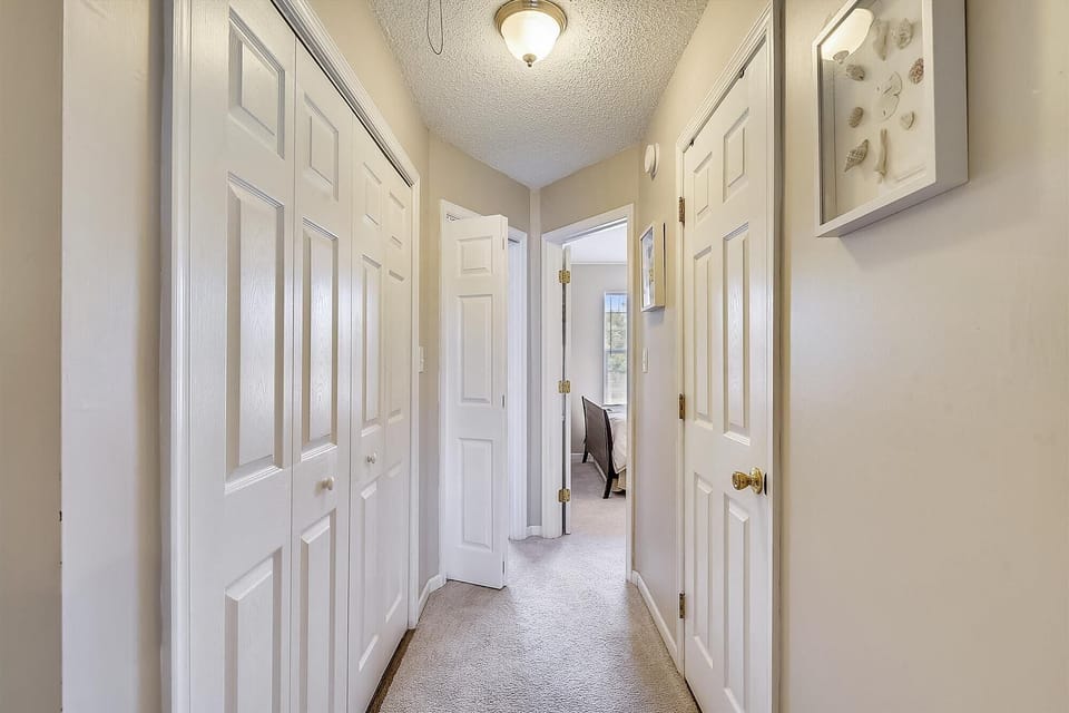 A bright hallway with abundant storage behind classic white doors leads you to the peaceful sleeping quarters, offering convenient access to all your vacation essentials.