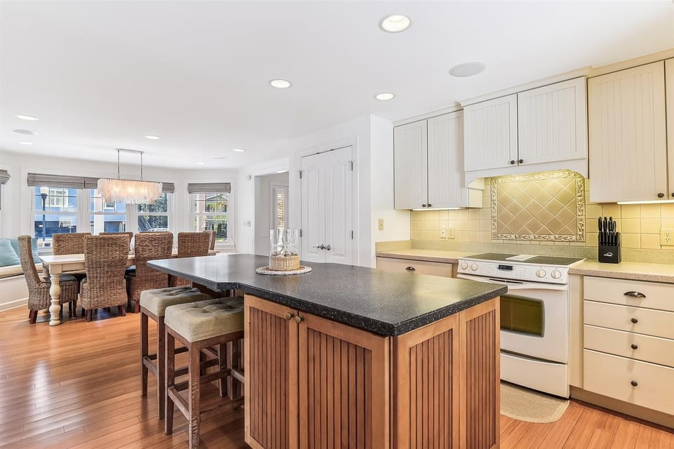 Gather around the spacious kitchen island with granite countertops and modern appliances at your fingertips. Natural light pours through large windows, illuminating warm wood floors and creating an inviting space where your group can cook, connect, and cre