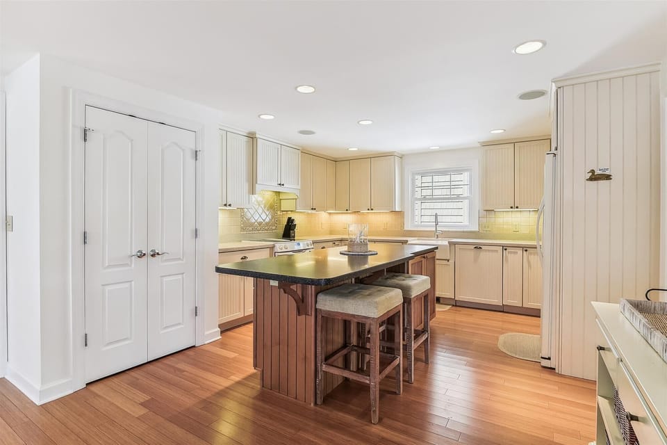 Cook your favorite meals in this bright, fully-equipped kitchen with a central island, custom cabinetry, and warm hardwood floors—perfect for your getaway.
